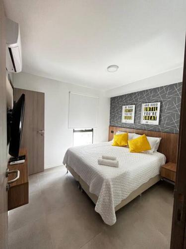 - une chambre avec un lit doté d'oreillers jaunes et une télévision dans l'établissement Moderno y delicado confort, à Santa Cruz de la Sierra