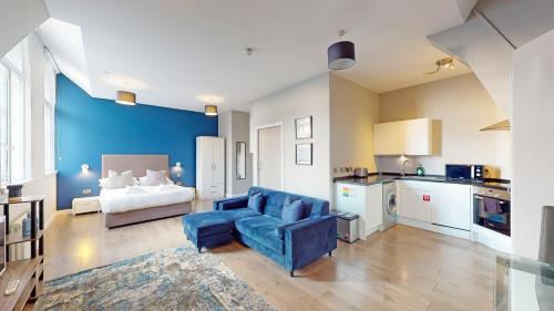 sala de estar con sofá azul y cocina en Glassford Residence, en Glasgow