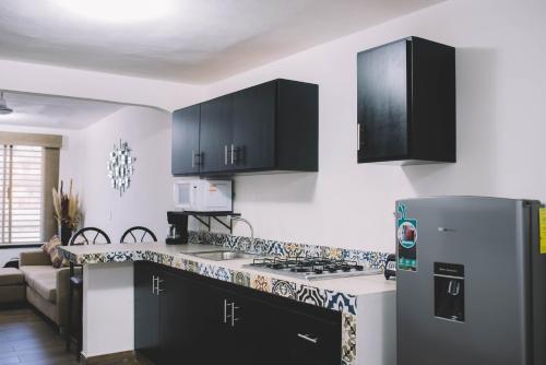 a kitchen with black cabinets and a stainless steel refrigerator at Departamento Mazatlán in Mazatlán