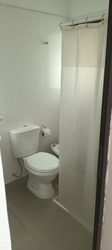 y baño blanco con aseo y ducha. en Los Nogales en Cafayate