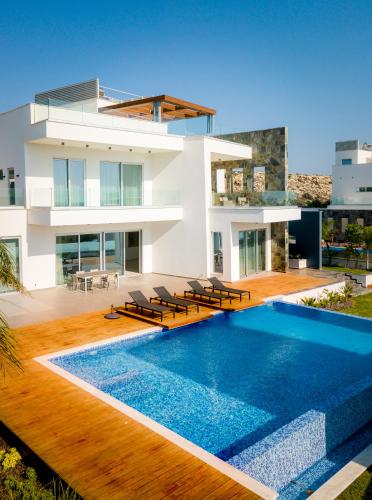 a house with a swimming pool in front of a house at Sea Pearl Beachfront Villas - Anemone in Ayia Napa