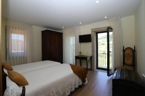 a bedroom with a large white bed and a balcony at New Honey House, Serra do Marão Ansiães-Amarante in Amarante
