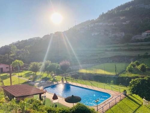 a large swimming pool in a field with a mountain at New Honey House, Serra do Marão Ansiães-Amarante in Amarante