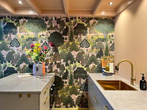 a kitchen with a wall with a floral wallpaper at Suite van Lotte in Dokkum
