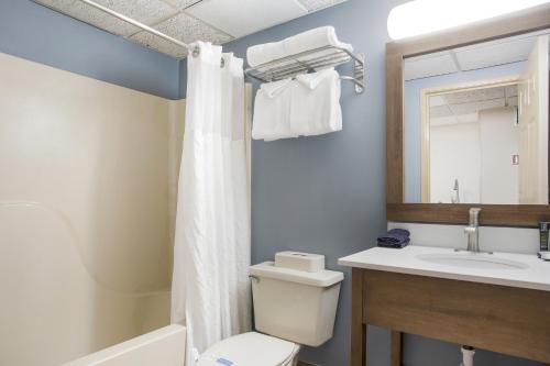 a bathroom with a toilet and a sink and a mirror at Americana Hotel Boardwalk in Ocean City