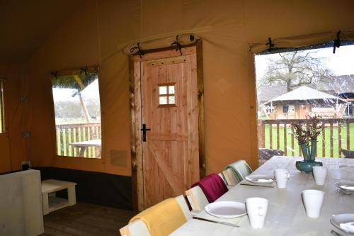 een tent met een tafel en stoelen en een deur bij Klein Koestapel in Putten