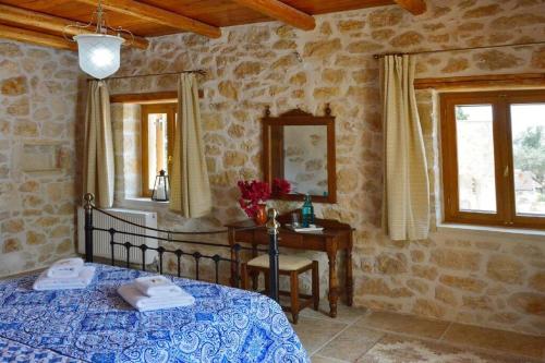 a bedroom with a bed and a table and windows at Villa Amalthiea in Arménoi