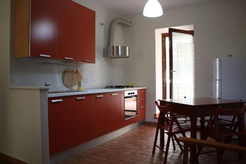 una cocina con armarios rojos y una mesa con sillas. en Casa&Cantina, en Senise