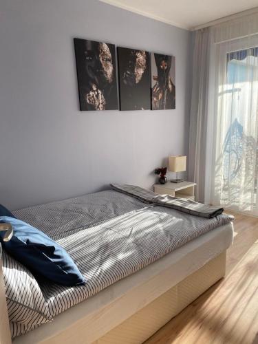 een slaapkamer met een bed met drie foto's aan de muur bij Belu Apartman in Balatonlelle