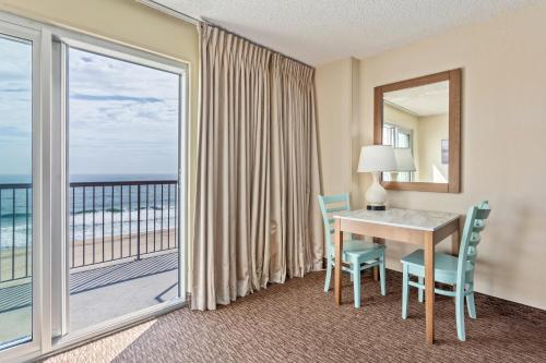 een hotelkamer met een tafel en uitzicht op de oceaan bij Americana Hotel Boardwalk in Ocean City