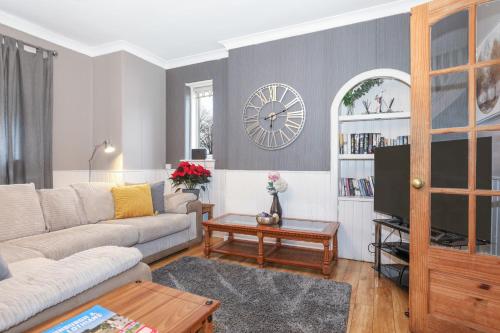 a living room with a couch and a clock on the wall at Beautiful Rooms in Edinburgh Cottage Guest House - Free Parking in Edinburgh