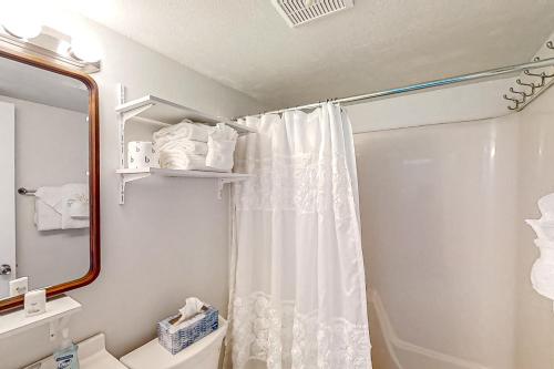 een badkamer met een douchegordijn en een spiegel bij Gold Coast Cottage 407 in Myrtle Beach