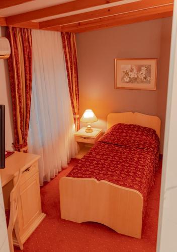 a bedroom with a bed with a red comforter at Hotel & Restaurant Se-Mi in Veliko Trgovišće