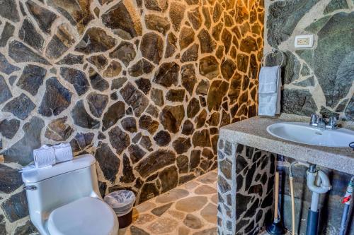 a stone bathroom with a toilet and a sink at Guapil #10 in Dominical