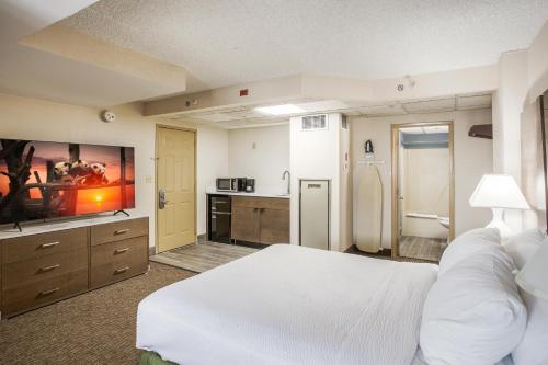 a large bedroom with a white bed and a bathroom at Americana Hotel Boardwalk in Ocean City