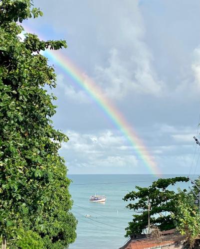a rainbow over the ocean with a boat in the water at Pousada dos Anjos Paracuru in Paracuru