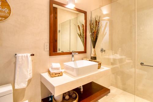 ein Bad mit einem Waschbecken, einem Spiegel und einer Dusche in der Unterkunft Amelia 104 Studio in Tulum