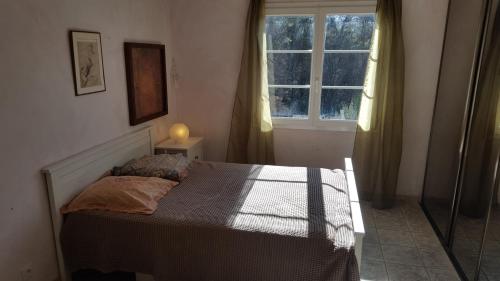 uma cama num quarto com uma janela em Mas des Marcellines em La Bouilladisse