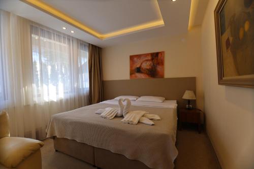 a bedroom with a bed with towels on it at Hotel Happy in Dimitrovgrad