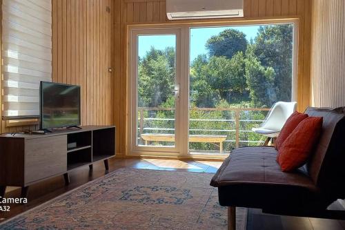 a living room with a tv and a large window at Cabaña Los Maquis en Castro in Castro