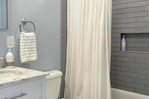 baño con cortina de ducha blanca y lavamanos en Patrician Shores Beach Abode, en Meredith