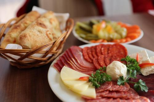 a table with plates of food and a basket of bread at Hotel Happy in Dimitrovgrad
