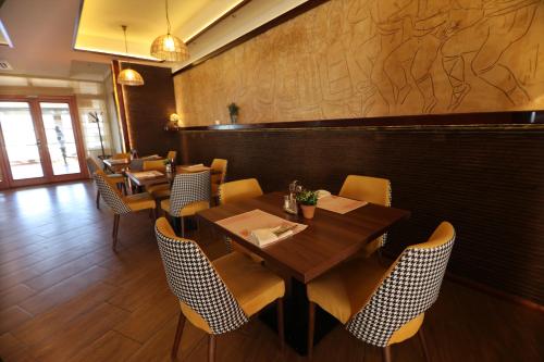 a restaurant with wooden tables and chairs and a wall at Hotel Happy in Dimitrovgrad