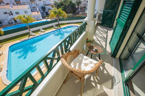 a balcony with a pool and a chair and a table at Holiday Albufeira in Albufeira