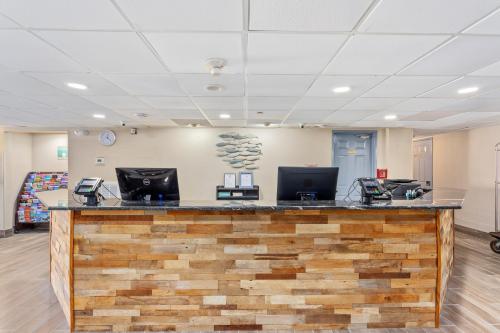 a lobby with a large wooden counter with two computers at Americana Hotel Boardwalk in Ocean City