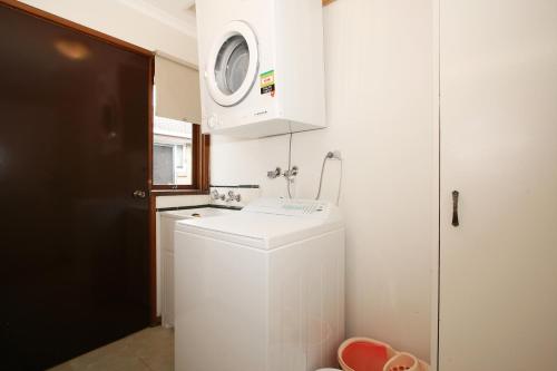 Una pequeña cocina blanca con lavadora y secadora. en Rent Melbourne, en Melbourne