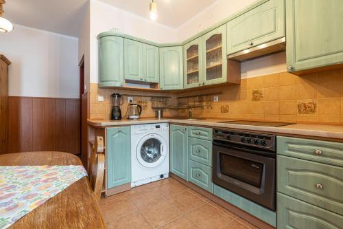 a kitchen with green cabinets and a washing machine at Pensjonat Beskidzki in Bielsko-Biała