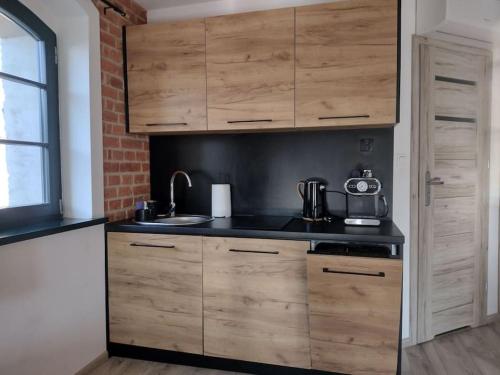 uma cozinha com armários de madeira e um lavatório em 13 Starówka apartament Miodova em Toruń