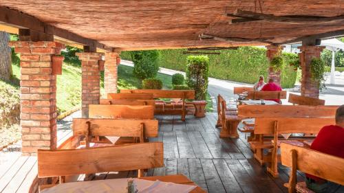 a restaurant with wooden tables and benches and people sitting at tables at Hotel & Restaurant Se-Mi in Veliko Trgovišće