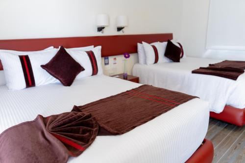 two beds in a hotel room with white and brown pillows at Mision Puebla Angelopolis in Puebla