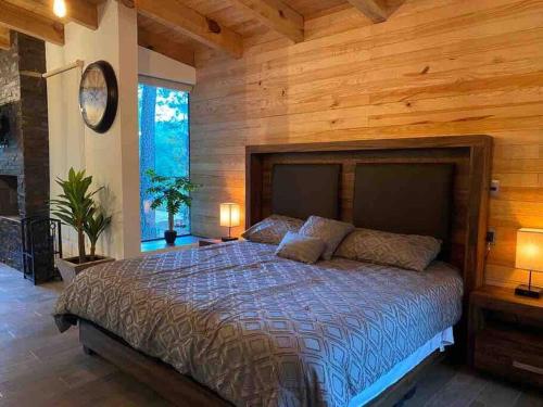 1 dormitorio con 1 cama grande y pared de madera en Cabaña Mazamitla con Jacuzzi hasta para 5 personas, en Mazamitla
