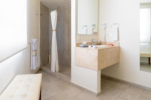 a white bathroom with a sink and a shower at Mision Puebla Angelopolis in Puebla