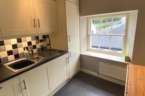 a kitchen with white cabinets and a sink and a window at Lovely 2 bedroom apartment in Kendal town centre in Kendal