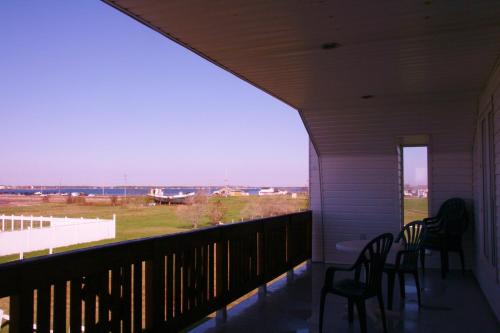 a porch with chairs and a view of a field at Escale de l'île - Auberge Janine du Havre in Shippagan