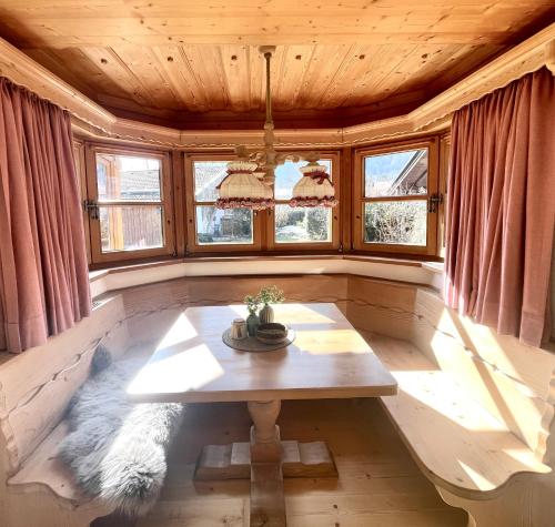 ein Esszimmer mit einem Tisch und Fenstern in der Unterkunft Ferienhaus Weißachdamm am Tegernsee in Rottach-Egern