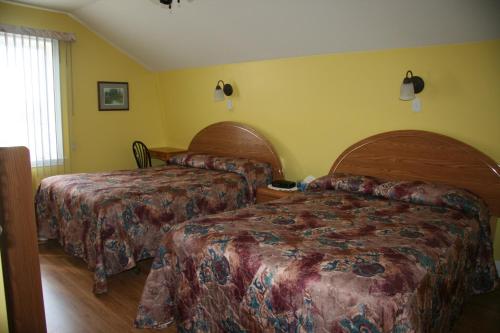 a hotel room with two beds and yellow walls at Escale de l'île - Auberge Janine du Havre in Shippagan