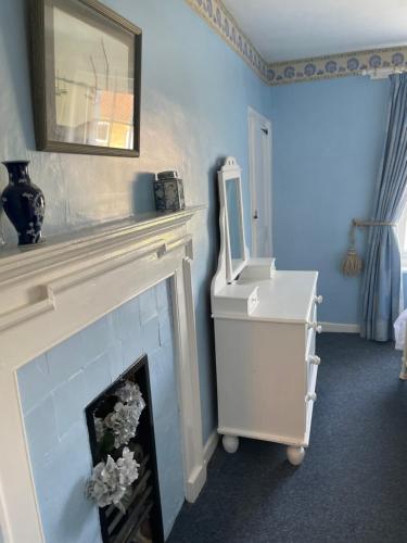 a blue room with a fireplace and a mirror at 2 bedroomed fisherman’s cottage near quay in Blakeney