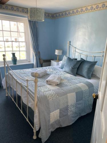 a bedroom with a bed with blue walls and a window at 2 bedroomed fisherman’s cottage near quay in Blakeney