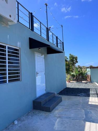 a white building with a staircase next to a door at Playa y Campo Studio in Isabela