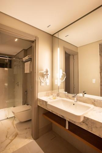 a bathroom with a sink and a toilet and a mirror at Amazon Aeroporto Hotel in Cuiabá