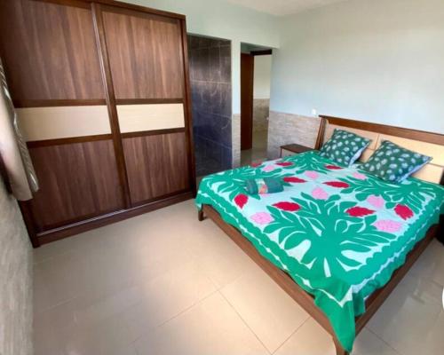 a bedroom with a bed with a green and white comforter at AUTE - Bord de mer - in Opoa