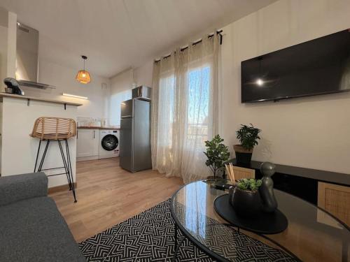 ein Wohnzimmer mit einem Tisch und einer Küche in der Unterkunft Appartement proche Disneyland in Coulommiers