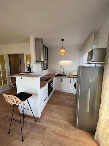 a kitchen with white cabinets and a stainless steel refrigerator at Appartement proche Disneyland in Coulommiers