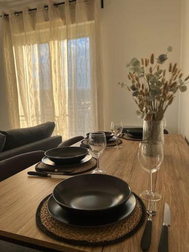 a wooden table with plates and wine glasses on it at Appartement proche Disneyland in Coulommiers
