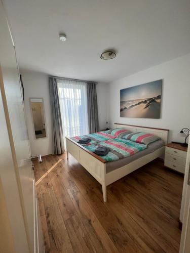 1 dormitorio con 1 cama y suelo de madera en Villa Lena - Wohnung Perlmutt, en Ostseebad Sellin