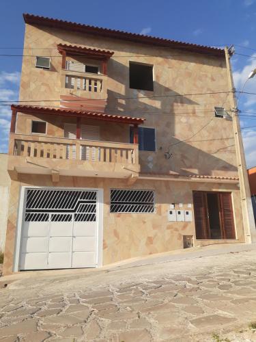 a house with two garage doors and a balcony at Pousada Nascer da Lua in São Thomé das Letras